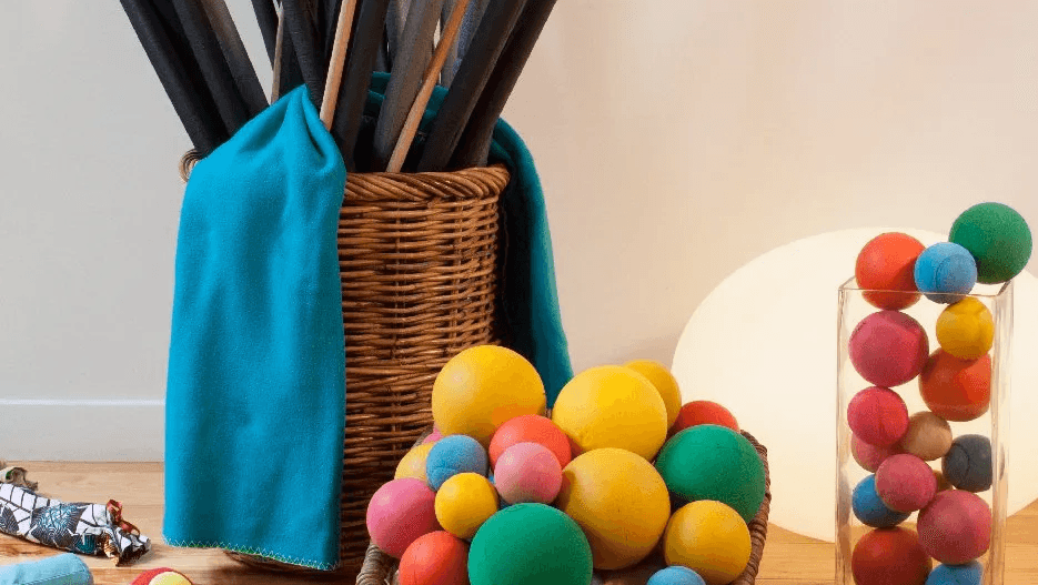 Matériel de séance : bâtons dans un panier d'osier, balles de mousse colorées et tissu turquoise