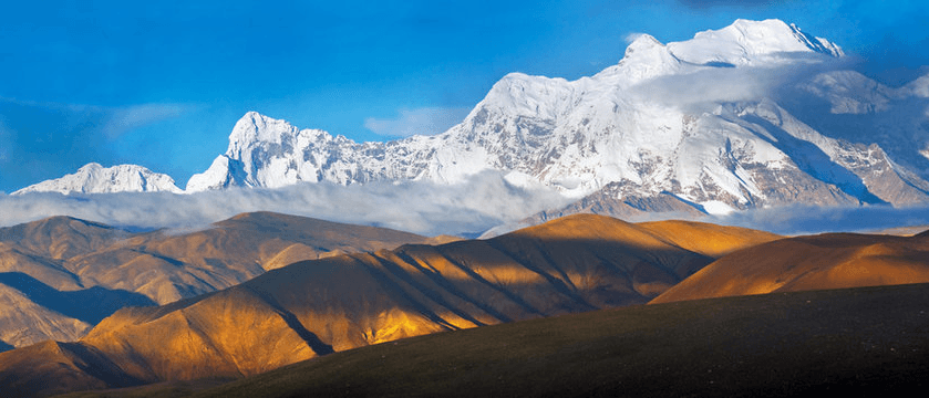 Sommets himalayens enneigés au-dessus de collines dorées