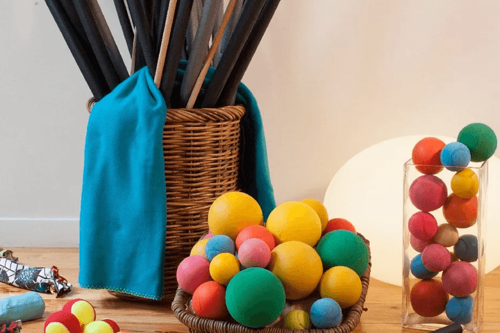 Matériel de séance : bâtons dans un panier d'osier, balles de mousse colorées et tissu turquoise